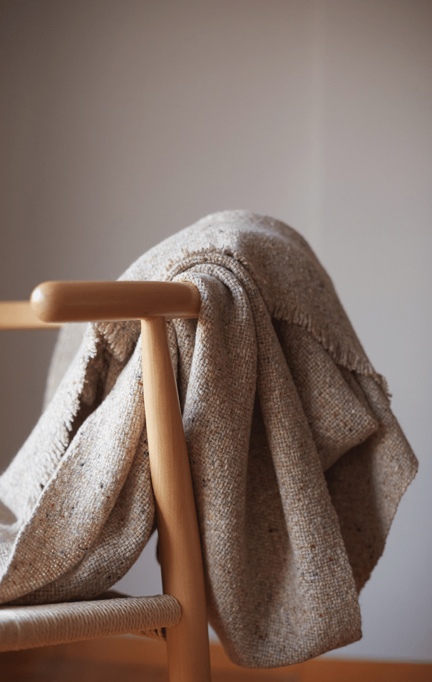 Wooden chair with a wool blanket and light grey background wall