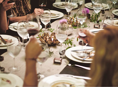 Several plates of food in front of guests at a dinner party 